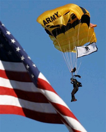 A member of the Army Black Knights parachutes past an American flag as part of the rededication ceremony
